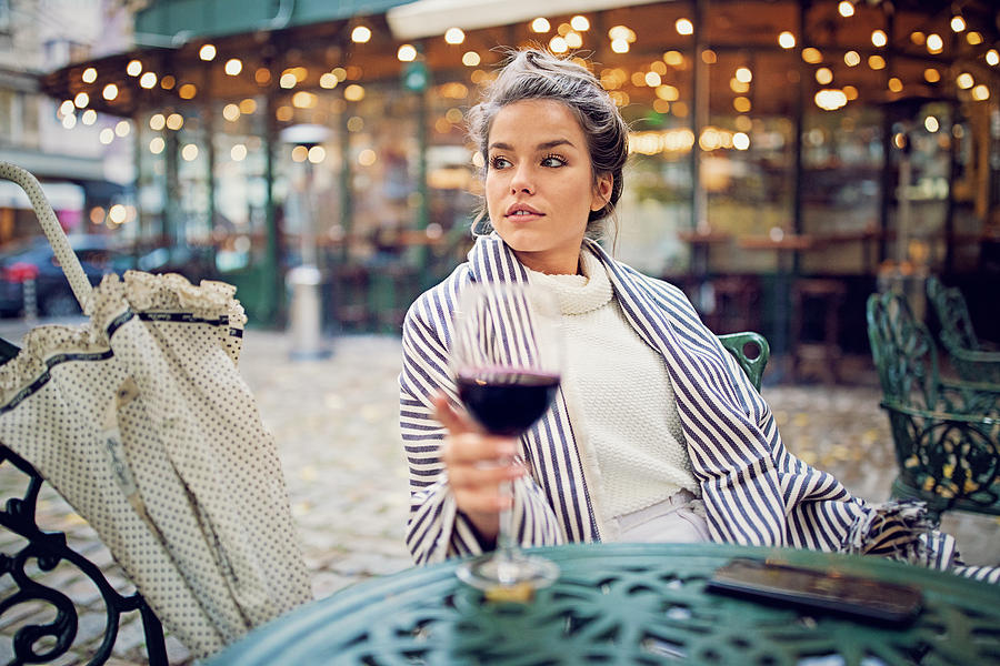 Young woman is drinking wine at the front of the cafeteria in a rainy day Photograph by Praetorianphoto