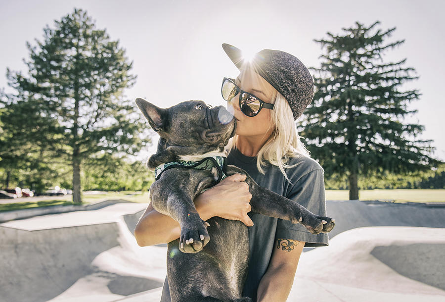Young woman kissing her dog at skatepark Photograph by Tony Anderson