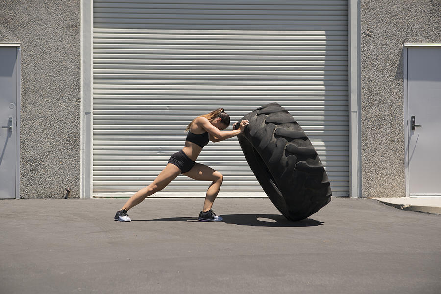 Young woman lifting a giant tire Photograph by Eternity in an Instant