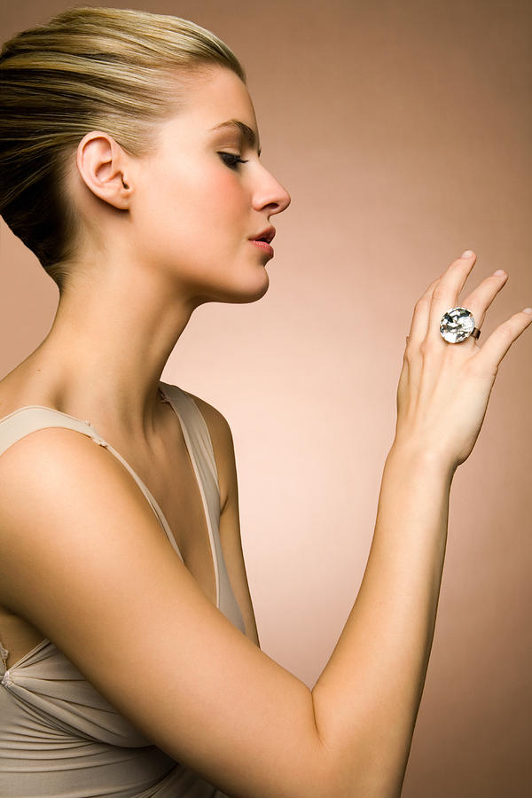 Young woman looking at diamond ring, close-up Photograph by Andreas Kuehn