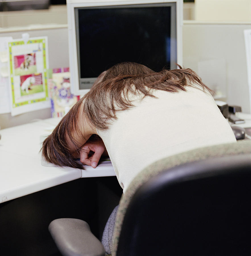 Young Woman Lying Head Down On Desk In Office Rear View By Holly