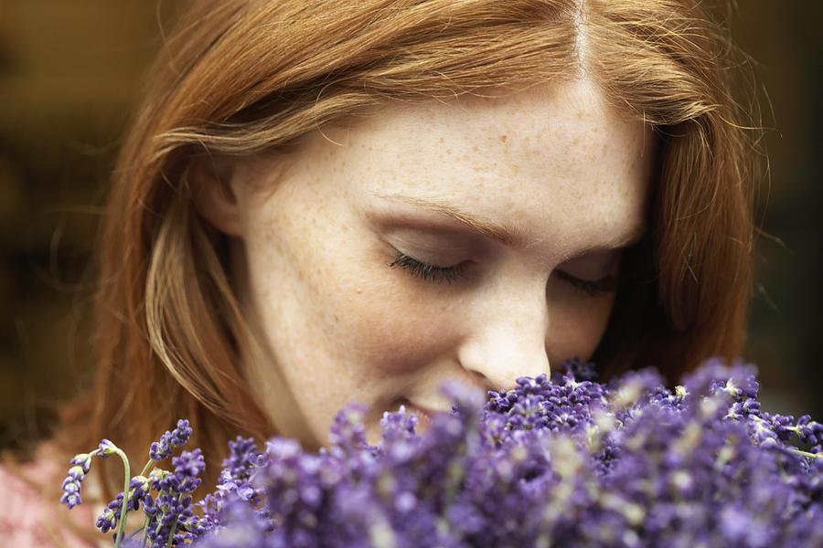 Young woman smelling lavendar, eyes closed, close-up Photograph by Tay Jnr