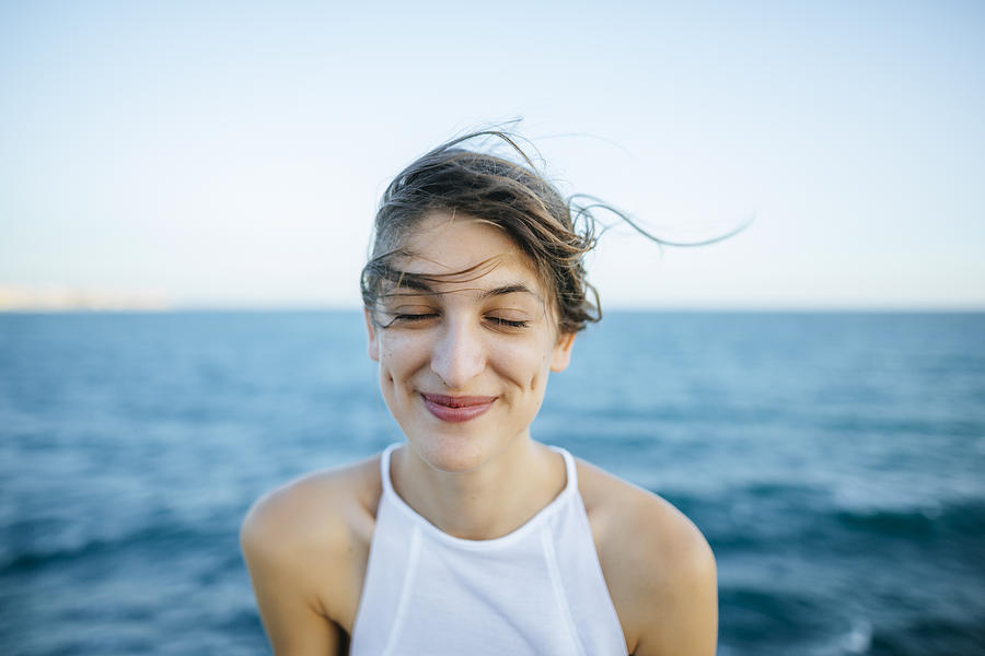 Young woman smiling with eyes closed with sea background Photograph by Westend61