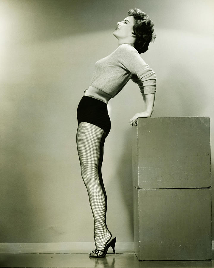 Young woman standing in studio, leaning backwards, (B&W) Photograph by George Marks