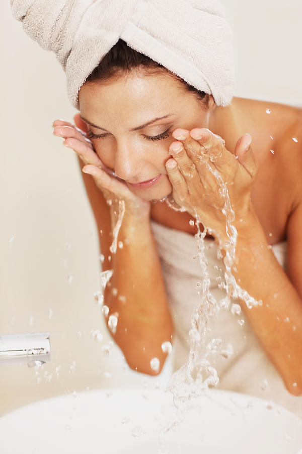 Young woman washing her face with water Photograph by GlobalStock