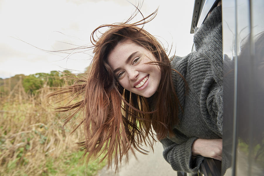 Young woman with head out of car window Photograph by Plume Creative