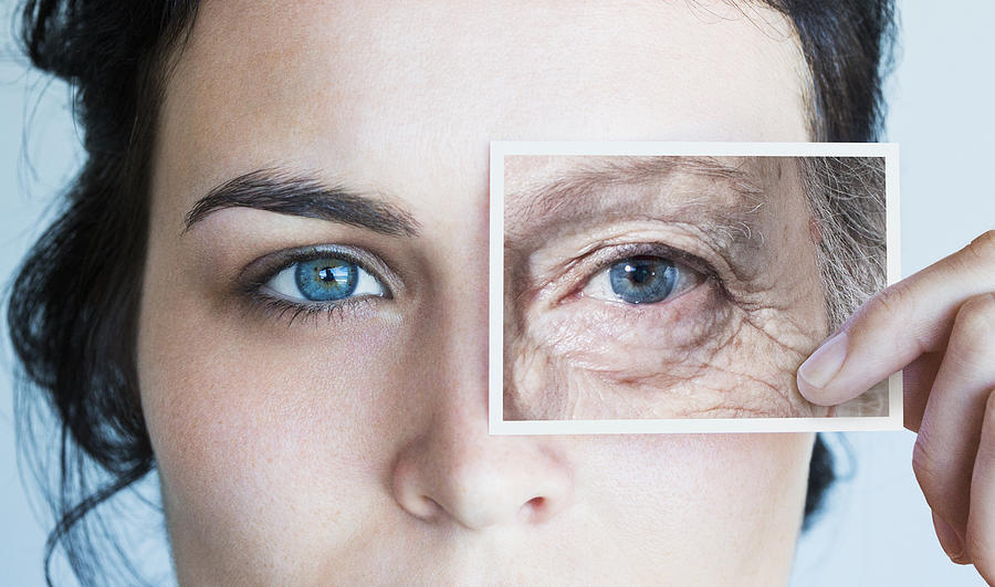 Young woman with photo of aged eye over her own Photograph by Dimitri Otis