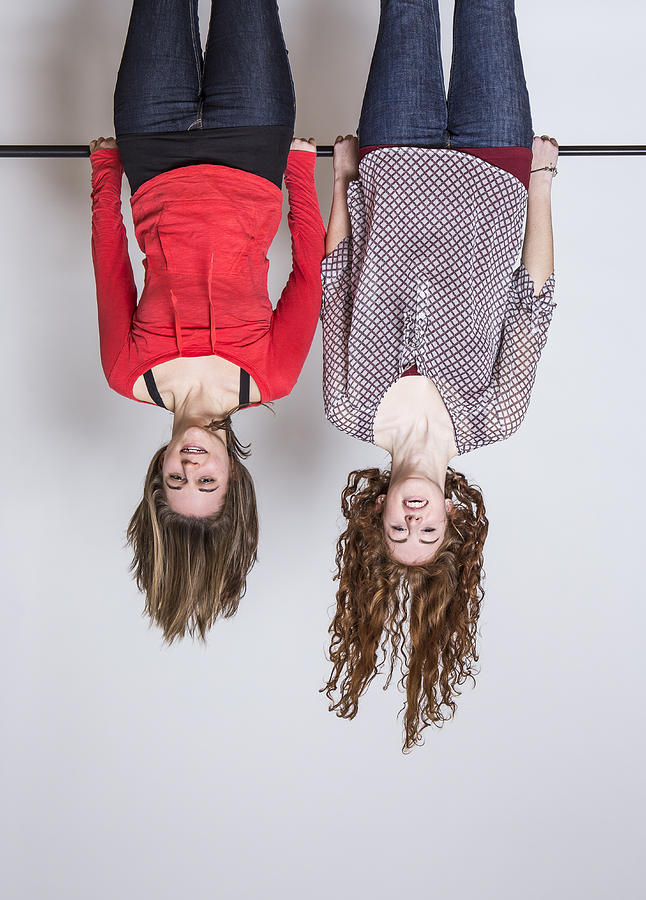 Young women hanging upside down, smiling Photograph by Westend61