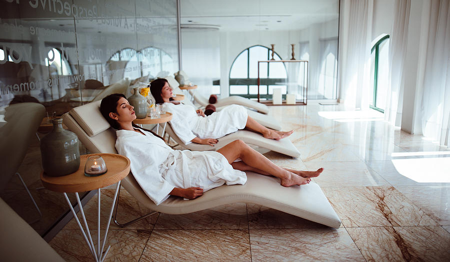 Young women in white robes relaxing at beauty spa centre Photograph by Wundervisuals