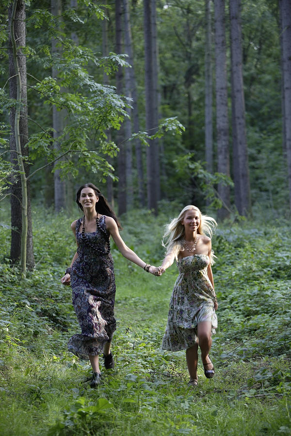 Young women running through forest Photograph by Asia Images
