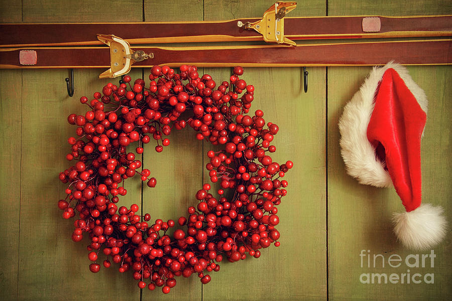 Christmas Photograph -  Red wreath with Santa hat hanging on rustic wall by Sandra Cunningham