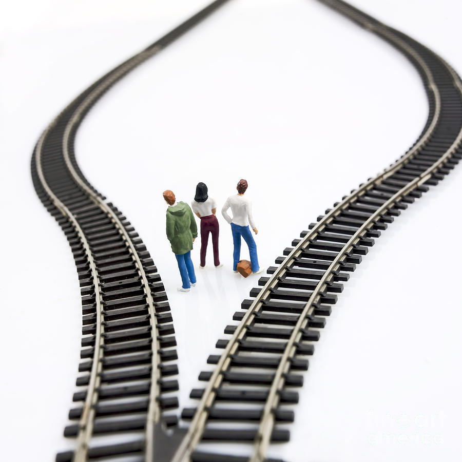 Reflective Photograph - Figurines between two tracks leading into different directions symbolic image for making decisions. #1 by Bernard Jaubert