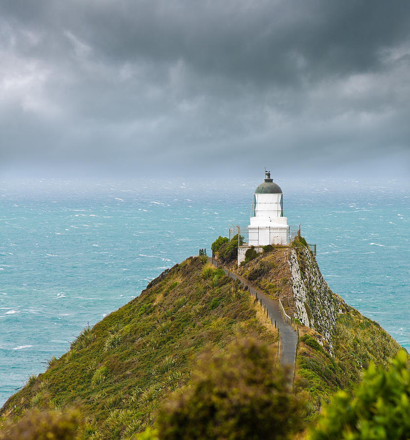 Nugget Point Light House and dark clouds in the sky #1 Photograph by U Schade