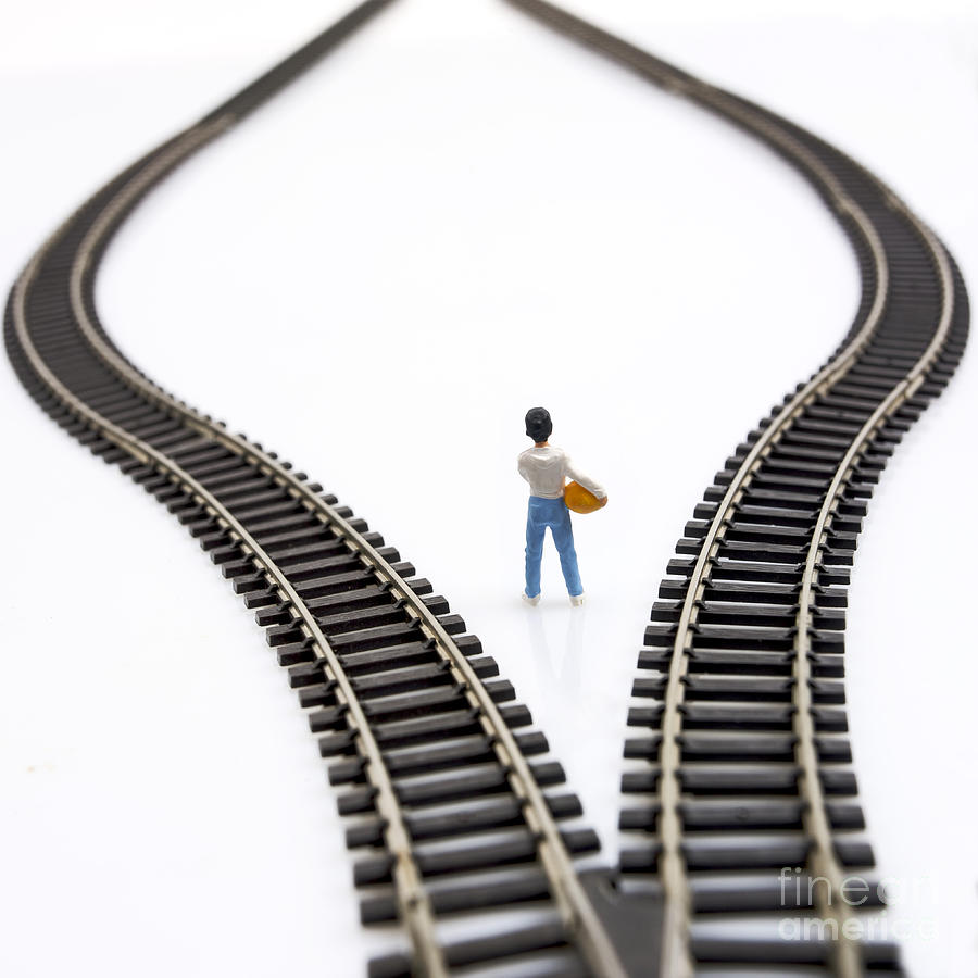 Decides Photograph - Figurine between two tracks leading into different directions symbolic image for making decisions. #2 by Bernard Jaubert