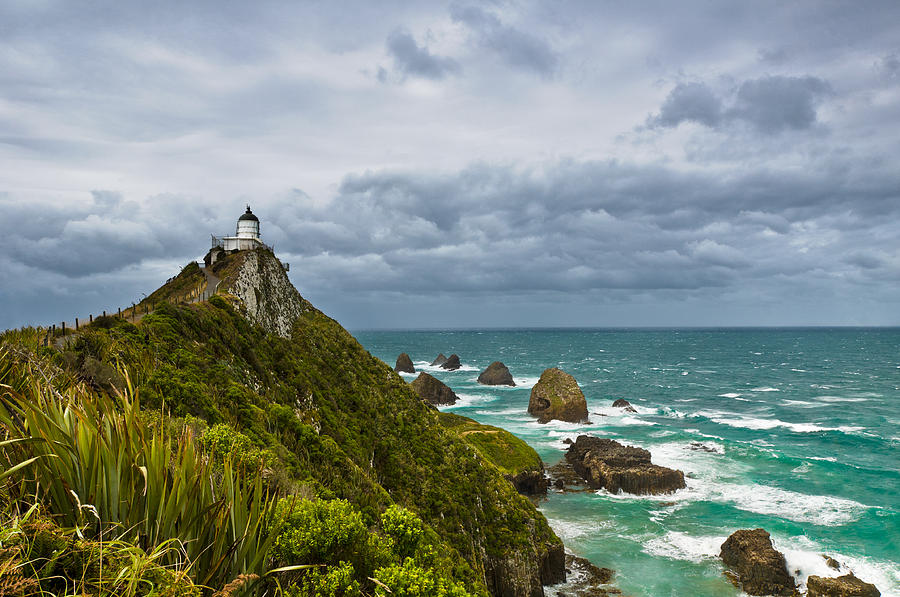 Nugget Point Light House and dark clouds in the sky #2 Photograph by U Schade