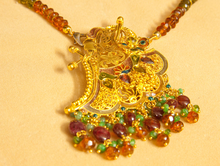 A beautiful intricately carved gold pendant hanging from a semi-precious stone chain Photograph by Ashish Agarwal