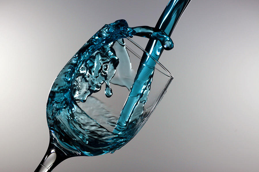 Blue Martini splashing from a wine glass Photograph by Paul Ge