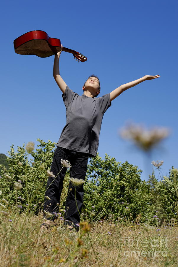 Boy standing in meadow with guitar Photograph by Sami Sarkis
