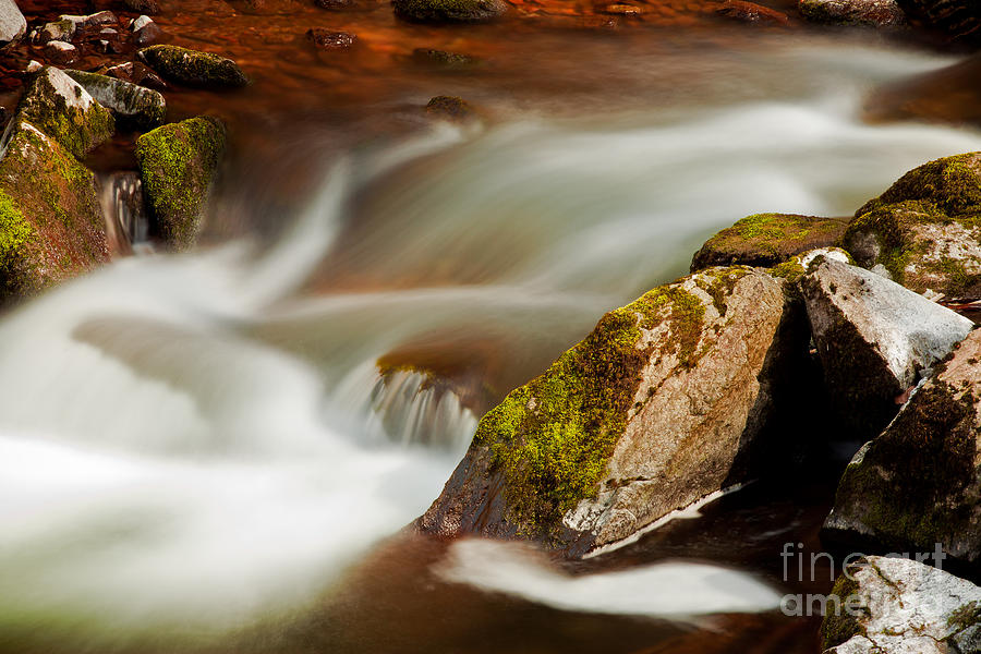 Flowing river blurred through rocks Photograph by Simon Bratt