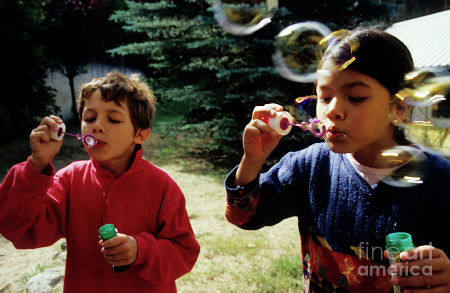 Girl and boy blowing bubble-wands Photograph by Sami Sarkis