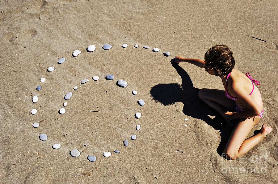 Beach Photograph - Girl on beach displaying pebbles in spiral shape by Sami Sarkis