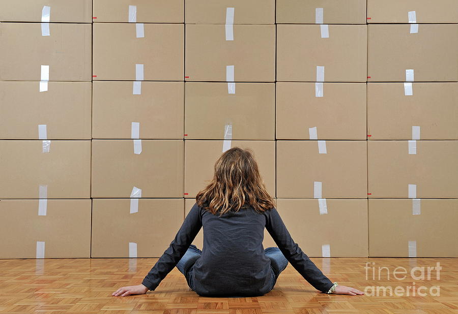 Girl seated in front of cardboard boxes Photograph by Sami Sarkis