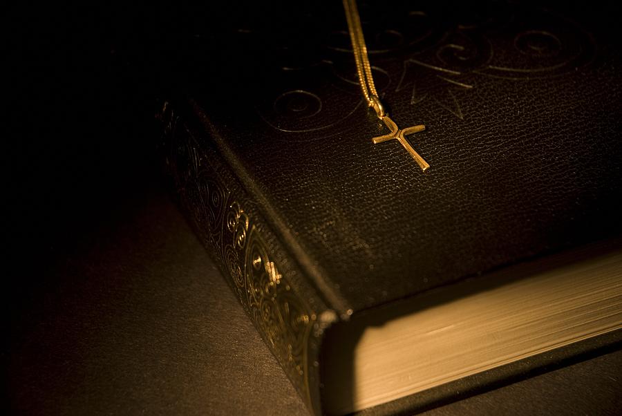 Gold Cross Pendant Resting On A Book Photograph by Philippe Widling