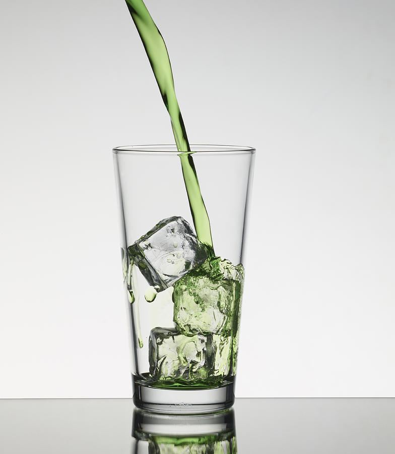 Juice Pouring Over Ice In Glass Photograph by Walter Zerla