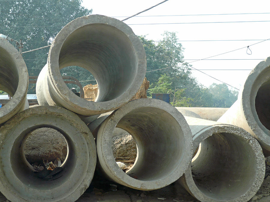 Large concrete sewage pipes piled up waiting for installation Photograph by Ashish Agarwal