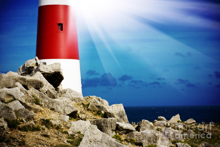 Lighthouse on rocks with light beams Photograph by Simon Bratt