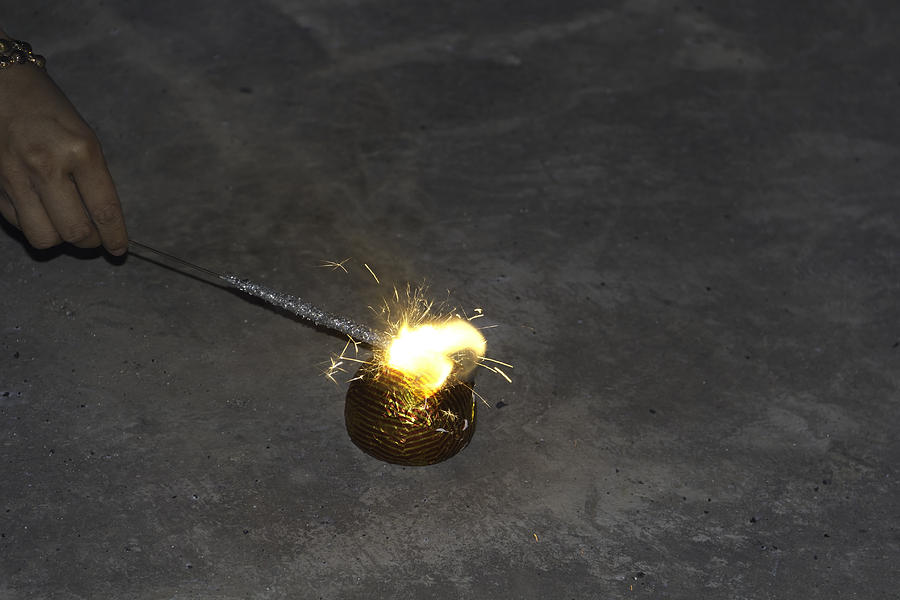 Lighting a firecracker using a sparkler as part of Diwali Photograph by Ashish Agarwal
