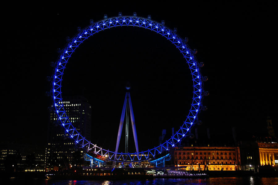 London Eye all done up in blue light in the night with a small reflection in the Thames Photograph by Ashish Agarwal