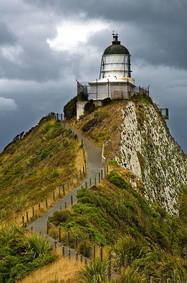Nugget Point Light House and dark clouds in the sky Photograph by U Schade