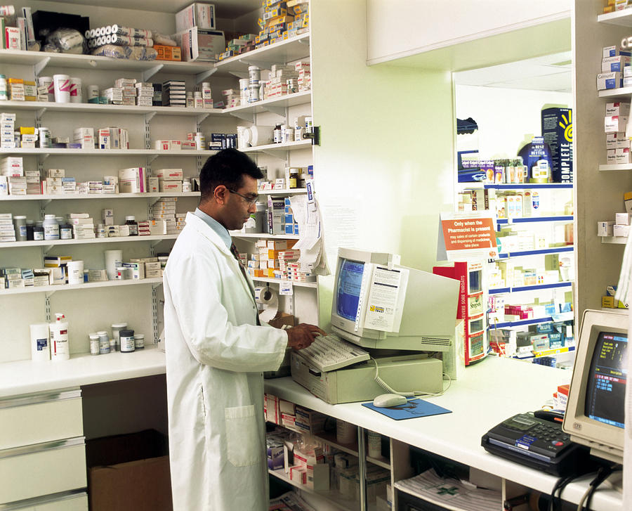 Pharmacist Using A Computer In A Pharmacy Photograph by Geoff ...