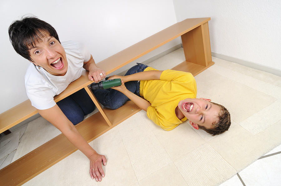 Screaming mother and son assembling furniture Photograph by Matthias Hauser