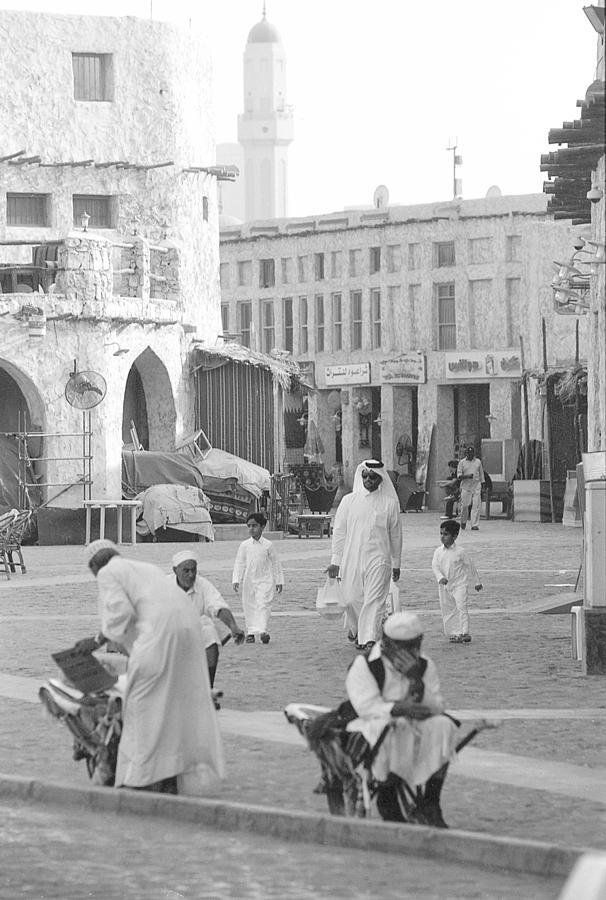 Shoppers and porters in Doha Photograph by Paul Cowan