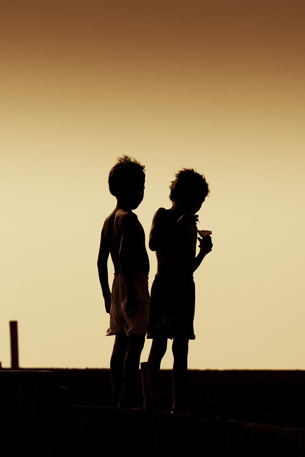 Sunset Photograph - Silhouette of Two Boys at the Beach by Tommy Fabianus
