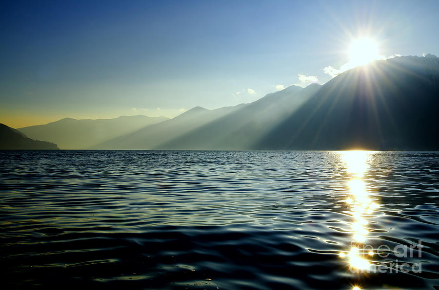 Sunlight over a lake with mountain Photograph by Mats Silvan