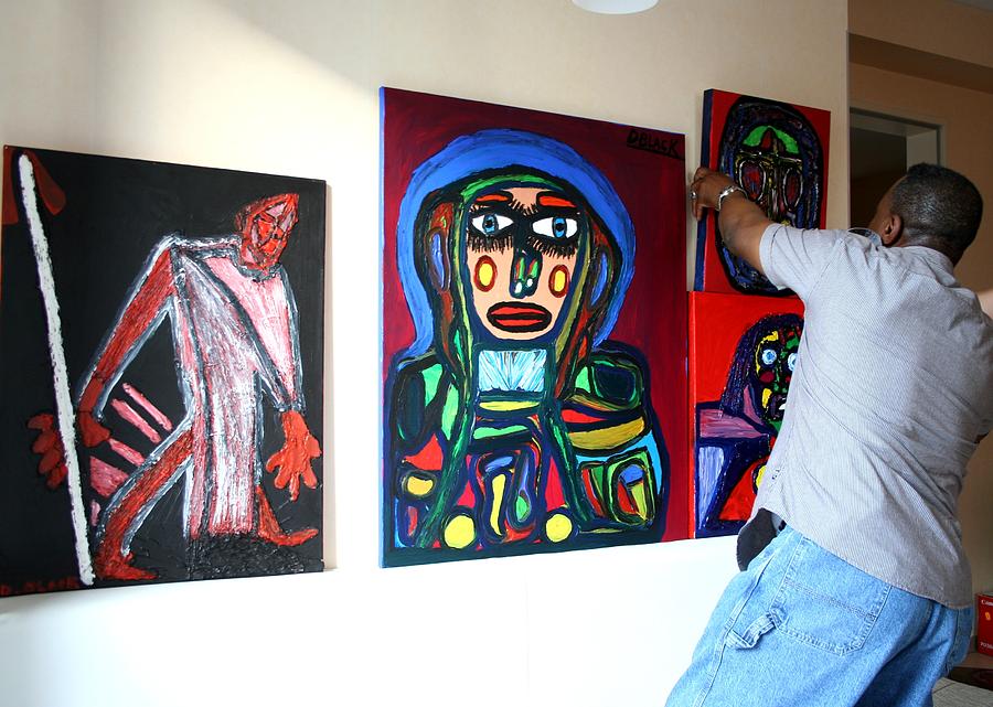 The artist Darrell Black in his studio hanging paintings Mixed Media by Darrell Black
