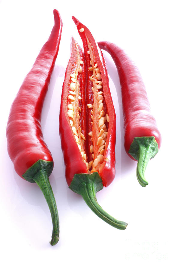 Three red chillis with one cut open Photograph by Simon Bratt