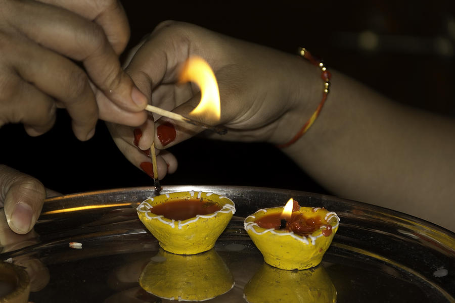 Trying to light an oil lamp that has gone out Photograph by Ashish Agarwal