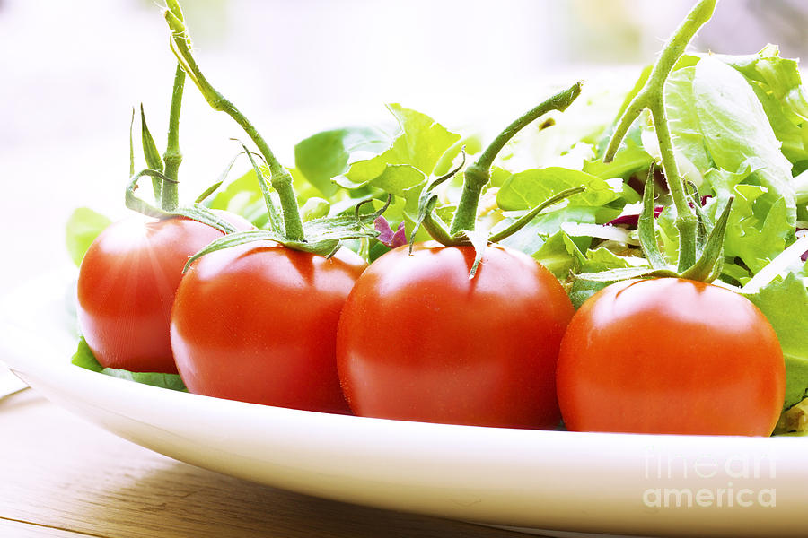 Vine tomatoes on a salad plate Photograph by Simon Bratt
