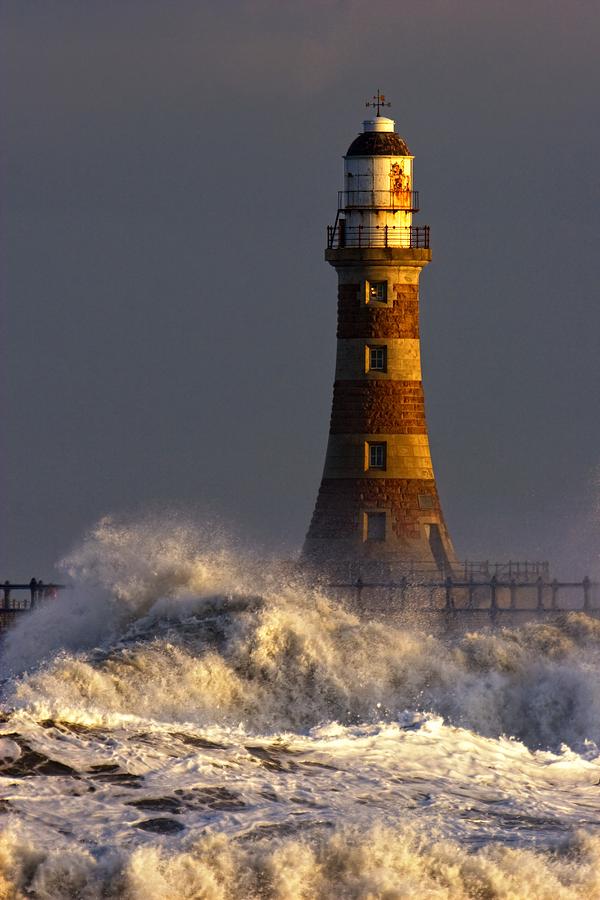 Waves Crashing Against A Lighthouse Photograph by John Short