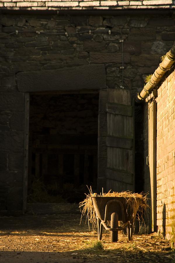 Barn Photograph - Wheelbarrow Beside A Barn by John Short