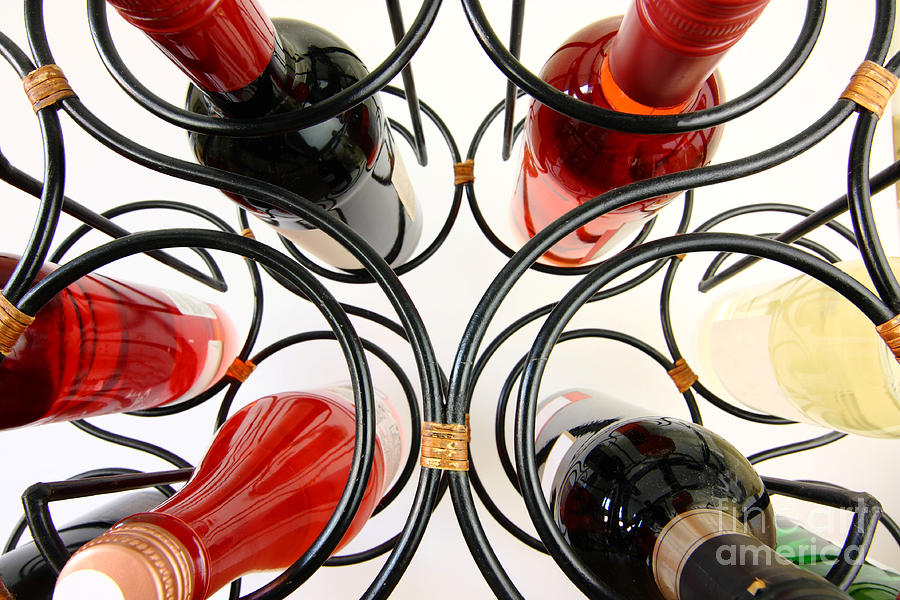 Wine bottles in curved wine rack Photograph by Simon Bratt
