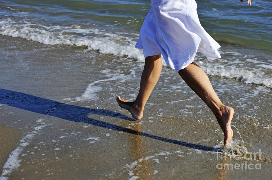 Woman running in water on beach Photograph by Sami Sarkis