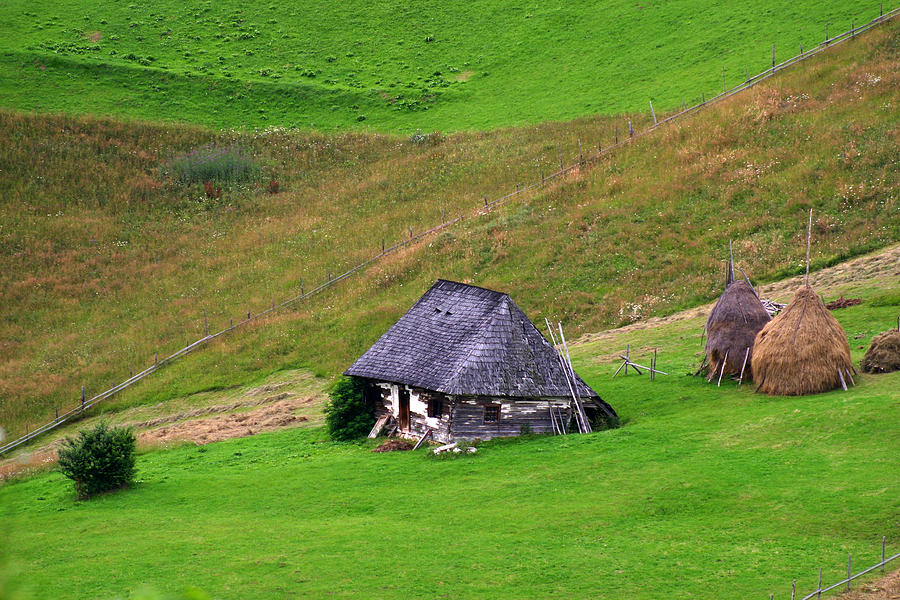 Wooden cottage and haystacks Photograph by Emanuel Tanjala