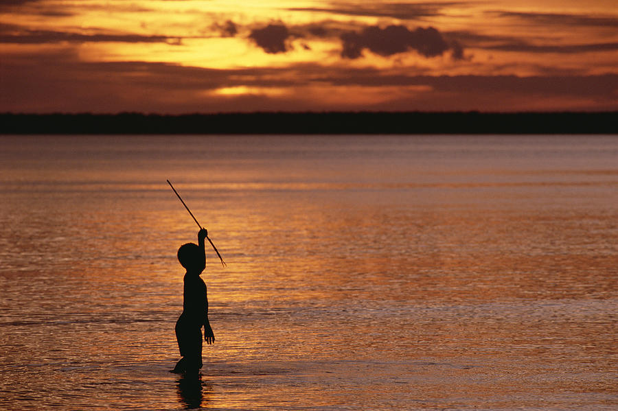 Young Boy Spear Fishing At Sunset by Gerry Ellis