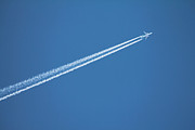 Airplane leaving vapor trail behind against blue sky Photograph by Bruno Guerreiro