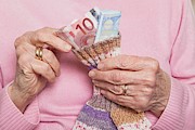 Germany, Senior woman counting money from money sock, mid section Photograph by Westend61